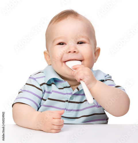Cute little boy is biting spoon