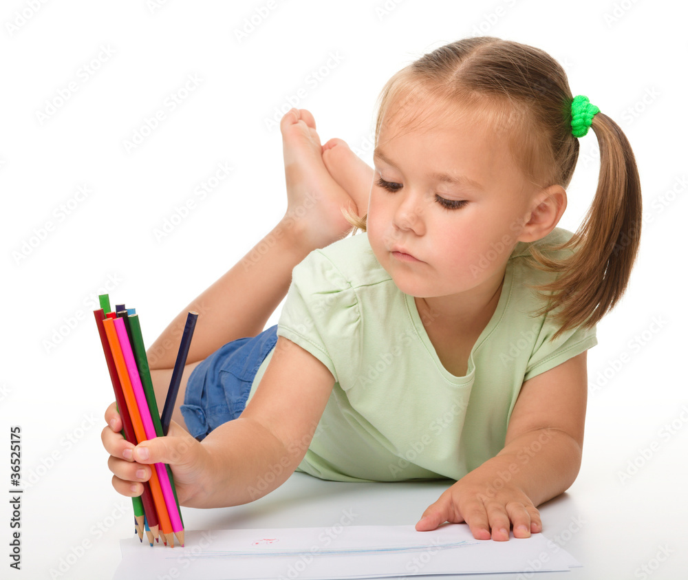 Little girl is drawing while laying on the floor Little girl is drawing while laying on the floor