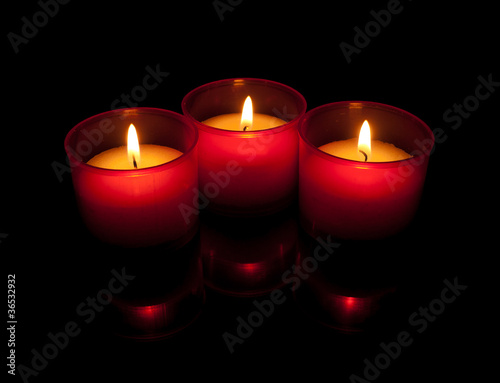 Three votive candles in red holders over black