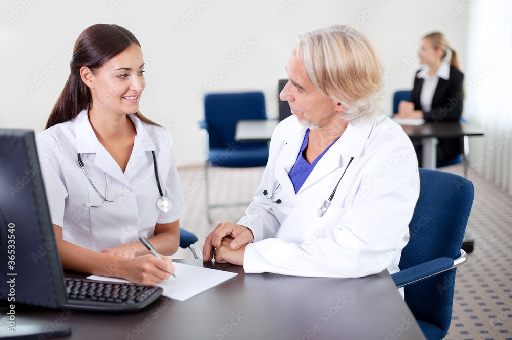 Young trainee sitting with a mature doctor Young trainee sitting with a mature doctor