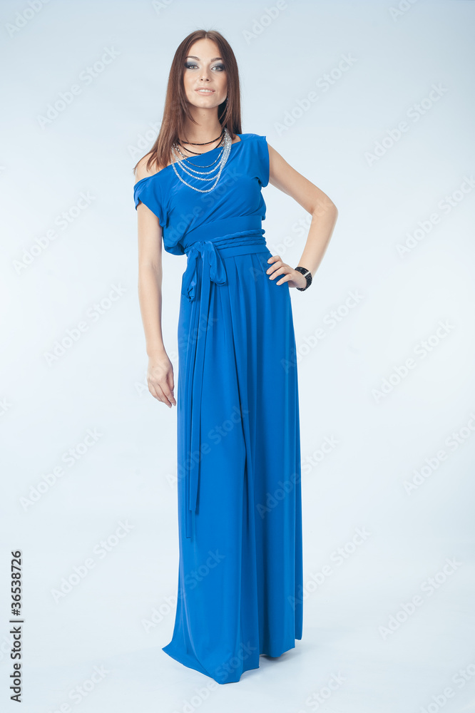 Young woman in blue dress posing in studio