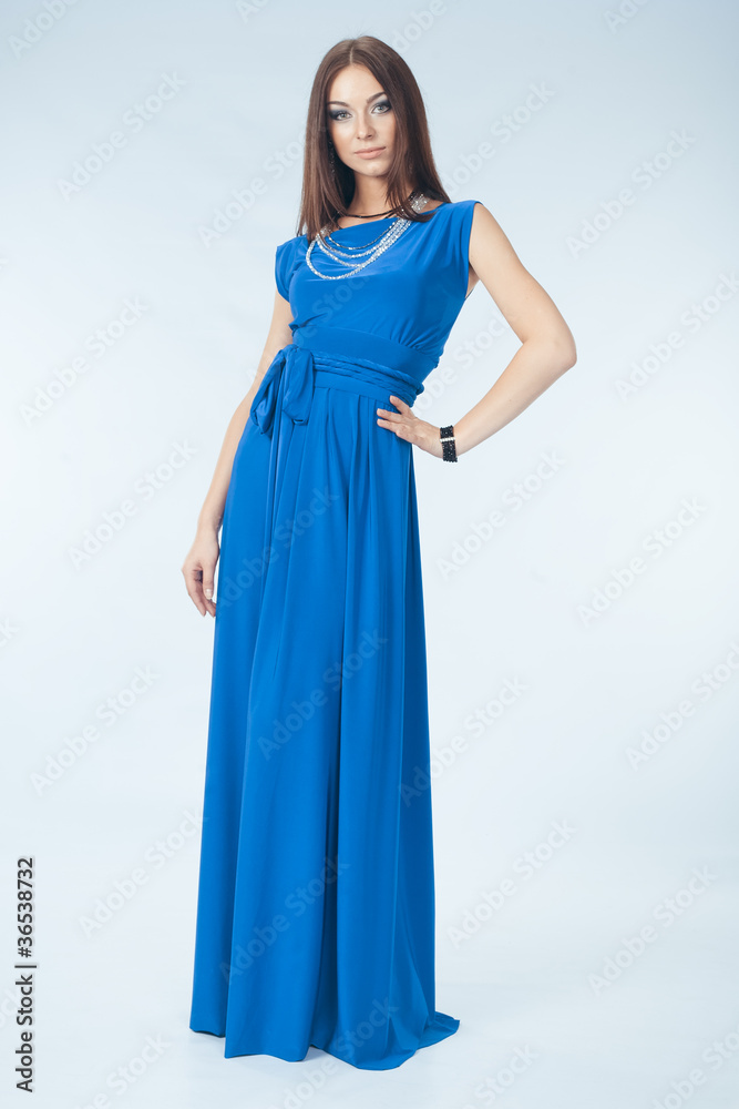 Young woman in blue dress posing in studio