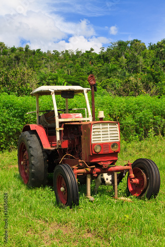 Old red tractor in a green field