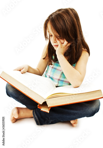 A little girl reading a book on the floor