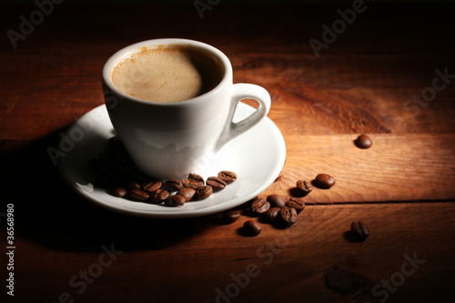 cup with coffee and coffee beans on wooden table