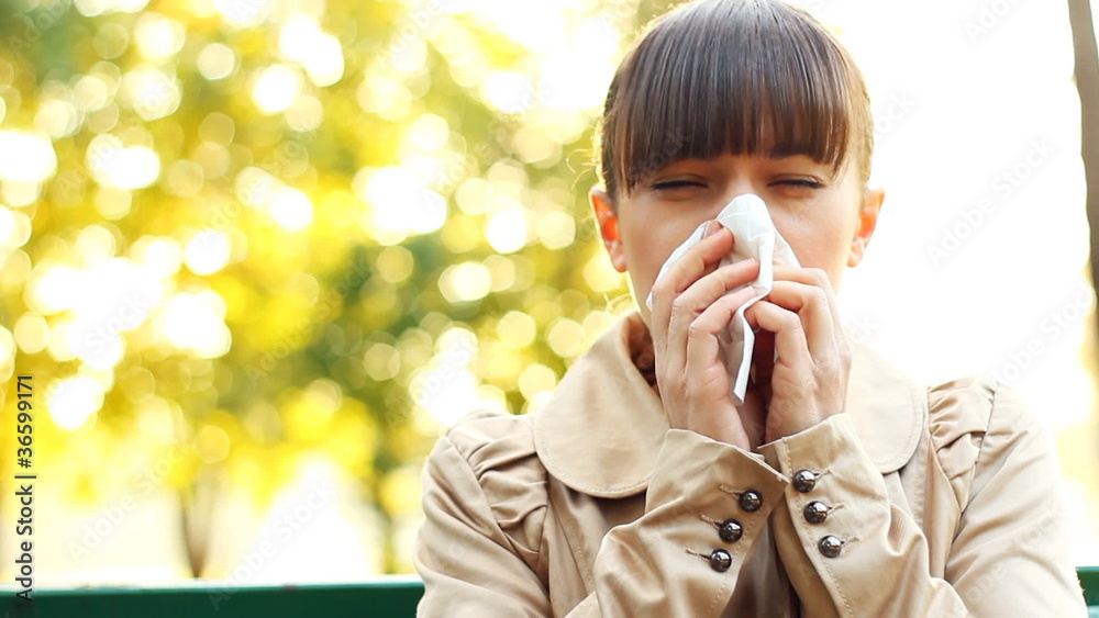 Sick woman blowing his nose into tissue, outdoors Sick woman blowing his nose into tissue, outdoors
