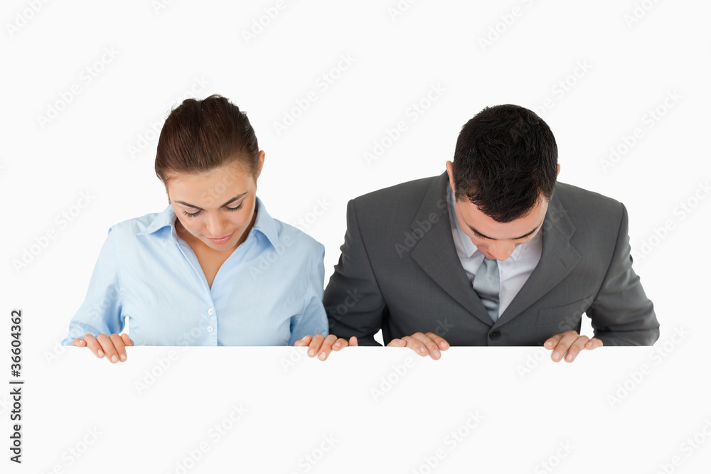 Business partners looking down at sign they are holding Business partners looking down at sign they are holding