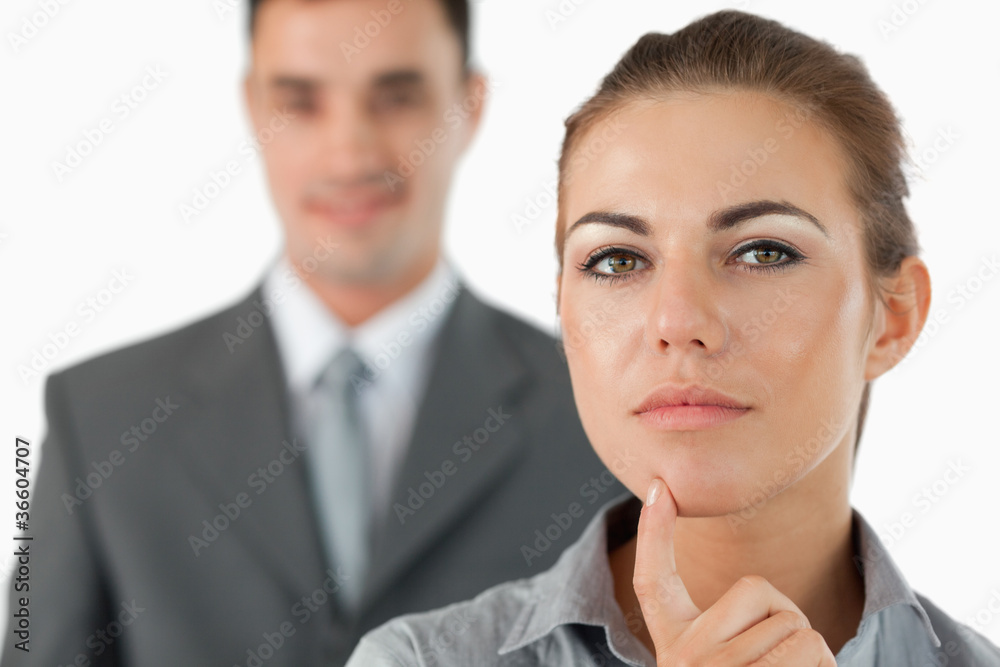 Close up of thinking businesswoman with colleague behind her Close up of thinking businesswoman with colleague behind her