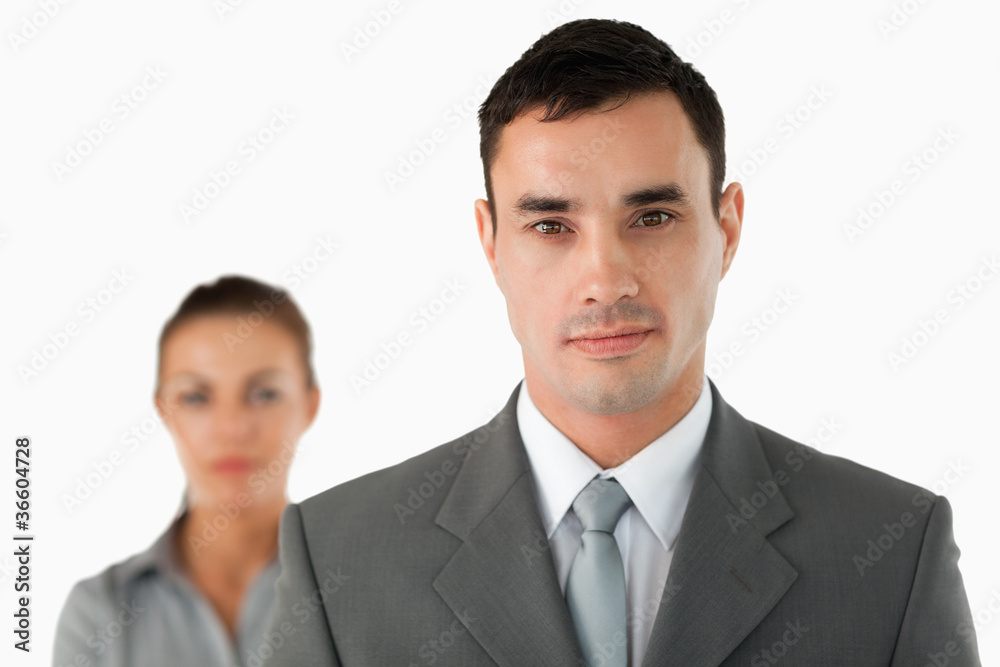 Close up of serious looking businessman with colleague behind hi Close up of serious looking businessman with colleague behind hi