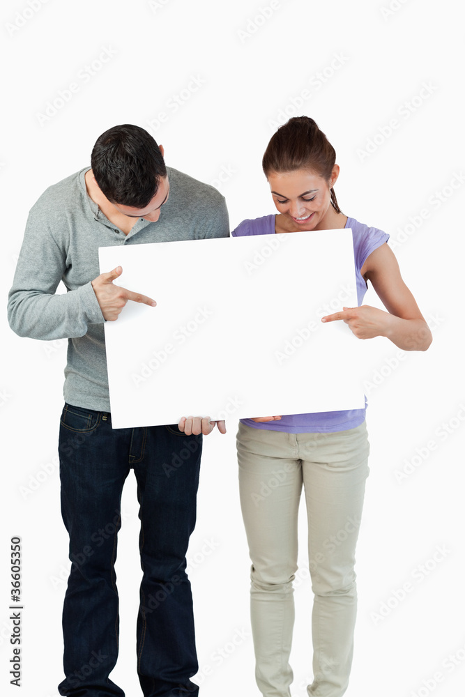 Young couple pointing at banner they are holding Young couple pointing at banner they are holding