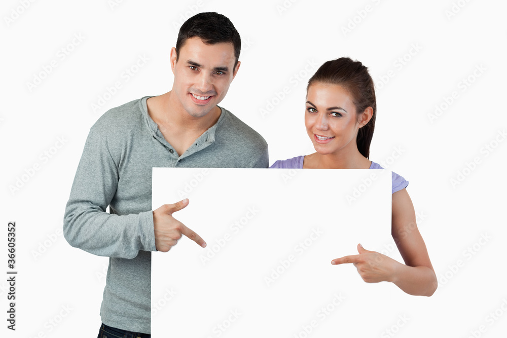 Young couple pointing at banner in front of them Young couple pointing at banner in front of them