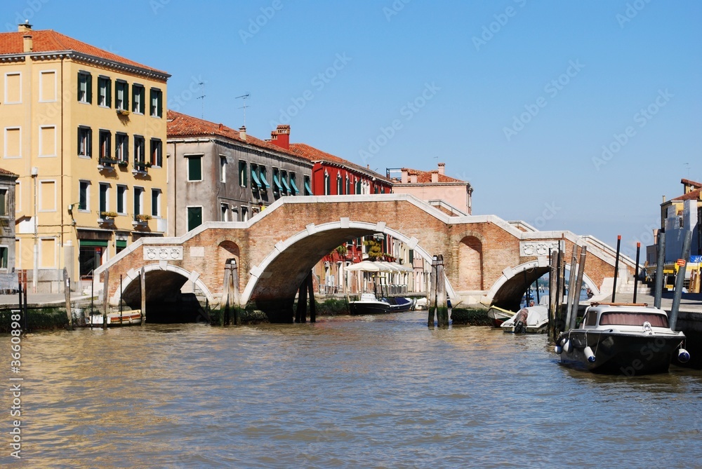 Stone bridge with three arches on a canal in Venice, Italy