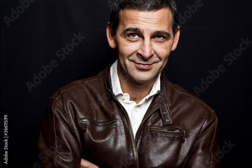 portrait of a cool mature man with leather jacket over black bac