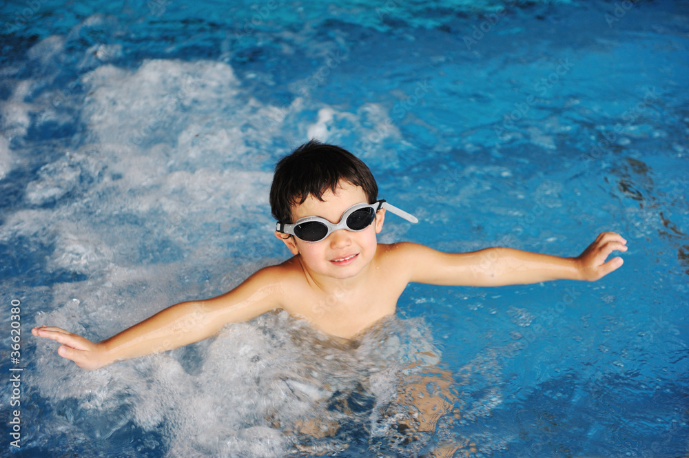 Little cute  boy in blue water of the swimming pool