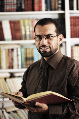 Young man reading book in library photo