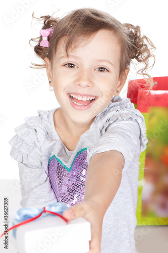 Happy smiling little girl giving you a present in studio