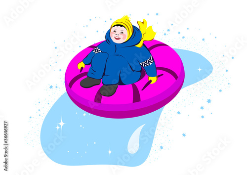 Boy sliding downhill on tube