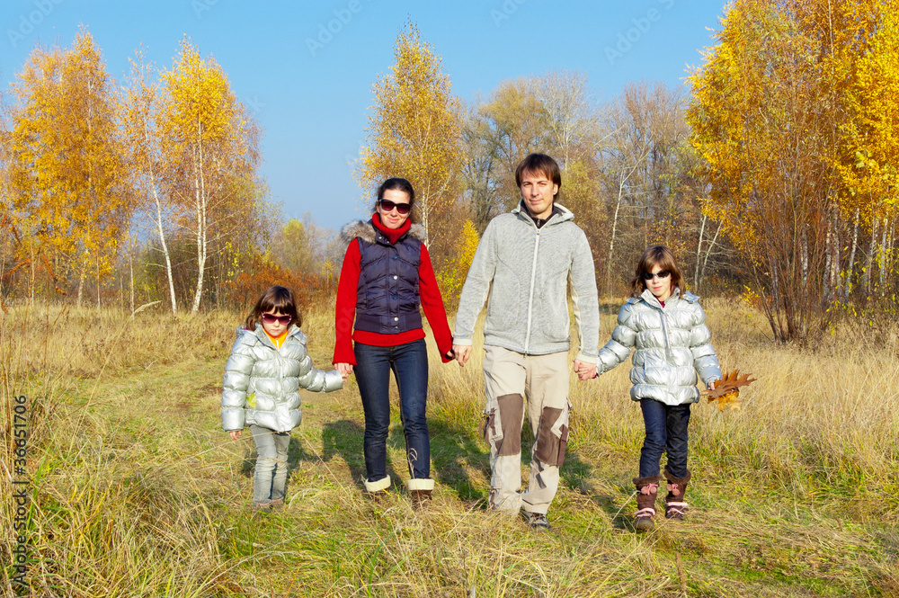 Happy smiling family walking in autumn park