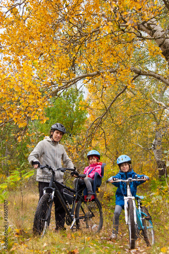 Family cycling outdoors, golden autumn in park, vertical photo