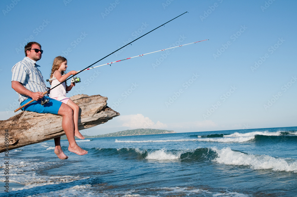 Fishing - little girl fishing with father at the beach Stock Photo