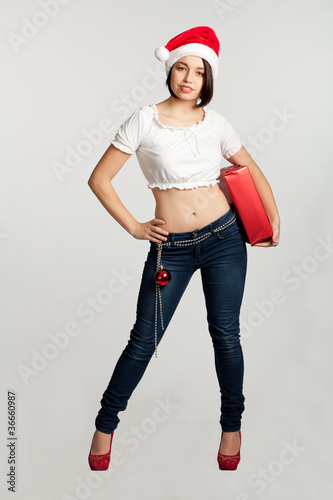 Smiling christmas girl holding gifts wearing Santa hat.