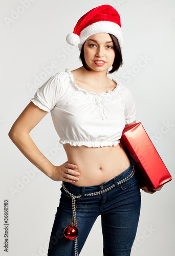 Smiling christmas girl holding gifts wearing Santa hat.