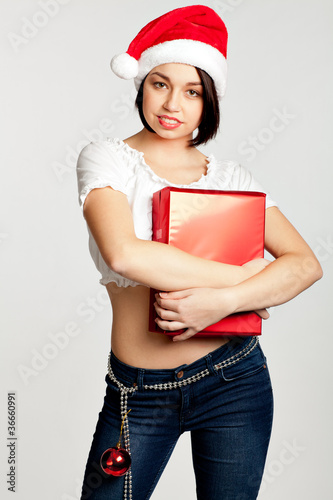 Smiling christmas girl holding gifts wearing Santa hat.