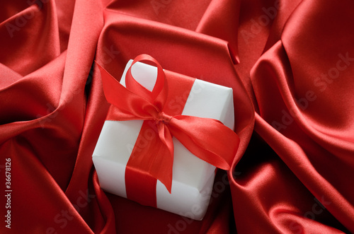 gift box with red ribbon bow on silk background