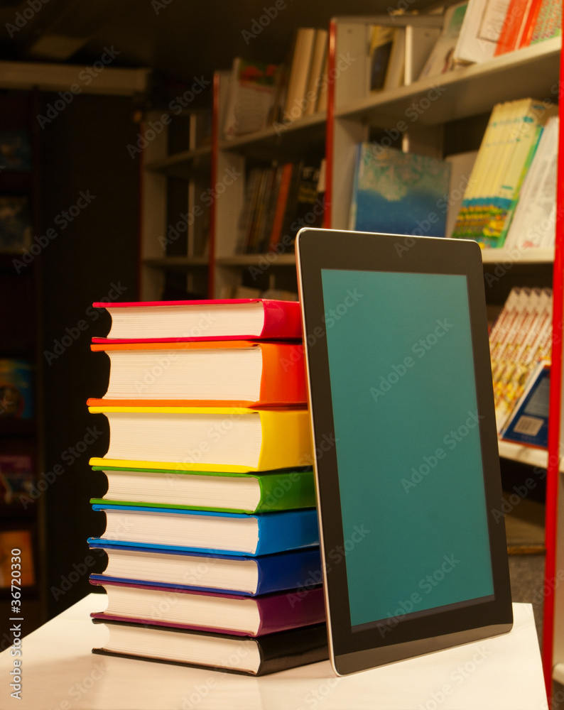 Stack of colorful books and electronic book reader