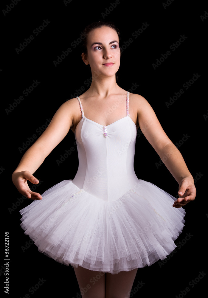 Fototapeta premium Teen girl ballet dancer standing in a tutu on a black background