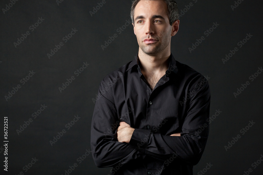 Obraz premium Man posing in black shirt on dark background in studio.