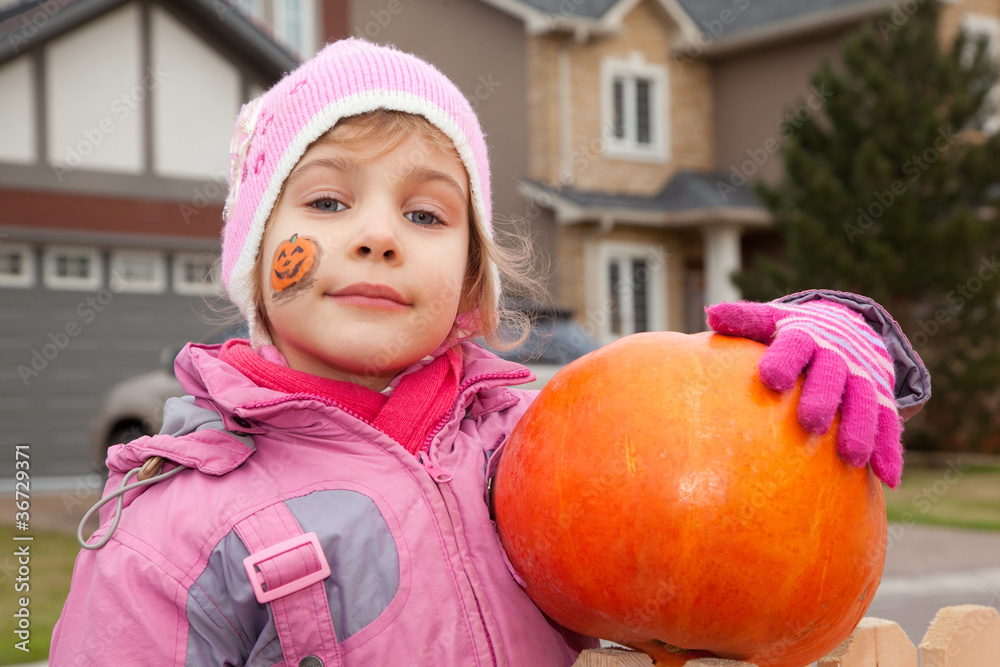happy little girl costs in court yard with pumpkin in hands happy little girl costs in court yard with pumpkin in hands