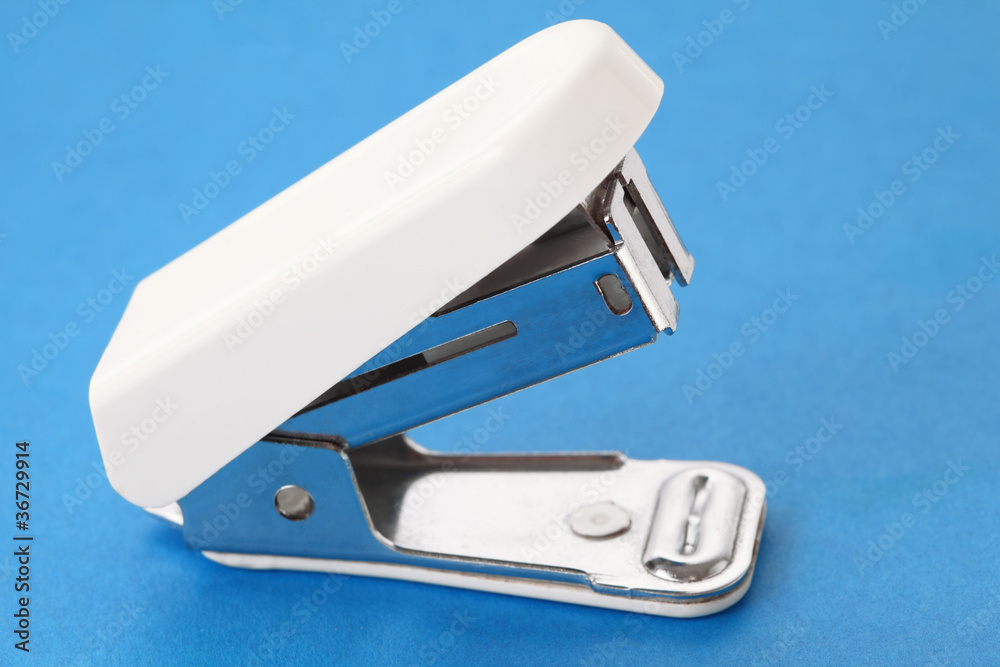 white plastic stapler for work of secretary on blue background white plastic stapler for work of secretary on blue background
