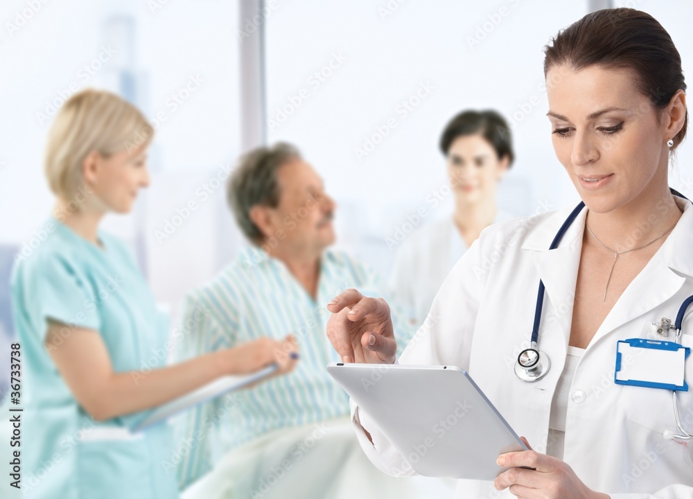 Doctor making notes at patients bed Doctor making notes at patients bed
