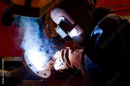 factory worker welding metal and sparks spreading
