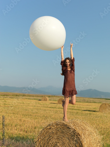 happy woman jumping white balloon hay stack
