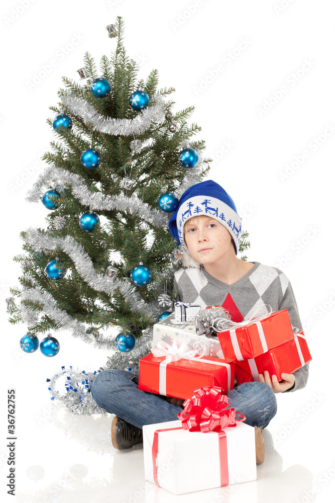 Pensive boy sitting near Christmas tree on the floor Pensive boy sitting near Christmas tree on the floor