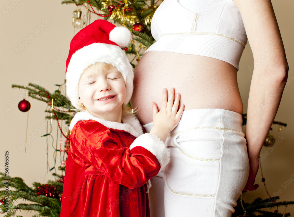 portrait of little girl and her pregnant mother by Christmas tre