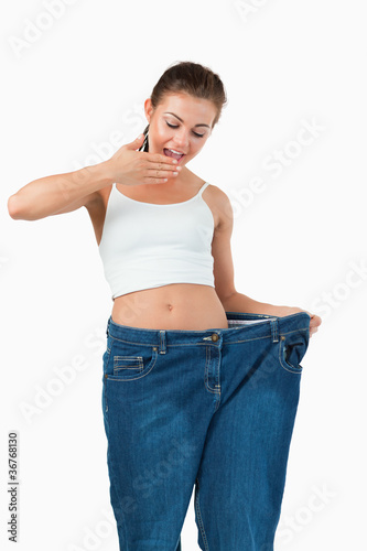 Portrait of a suprised woman wearing too large jeans