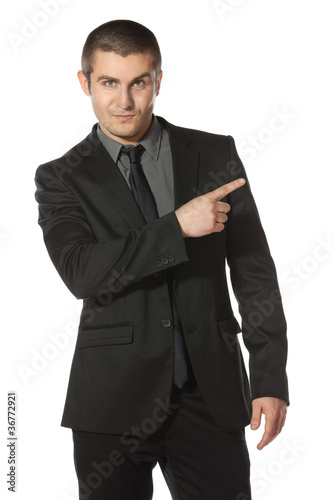 Young business man in suit pointing at copy space