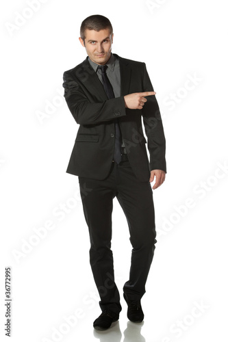 Full length of young business man in suit pointing