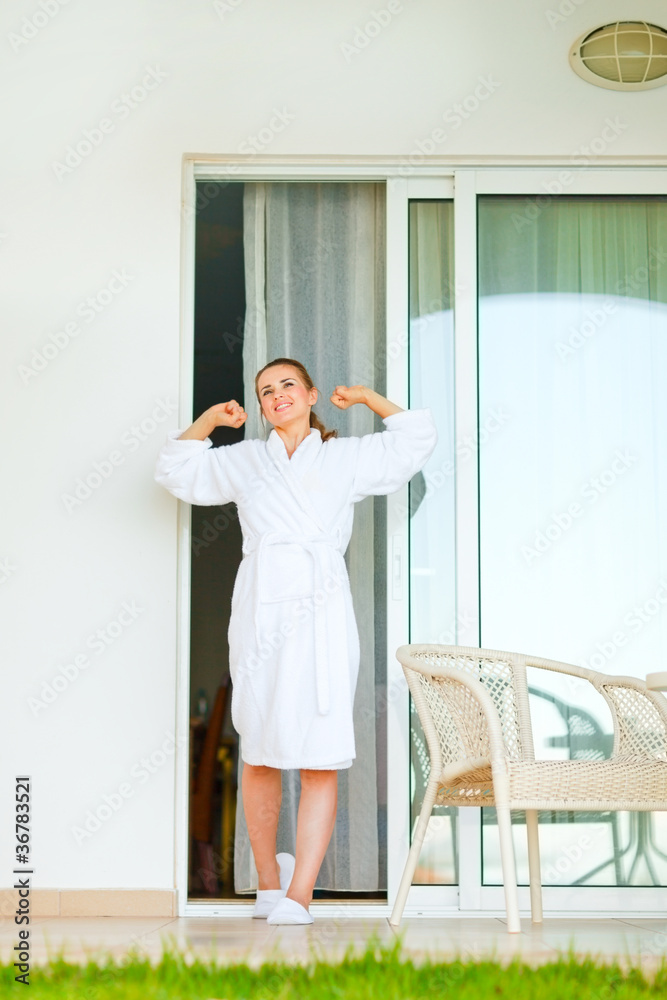 Beautiful woman in bathrobe coming out on on terrace