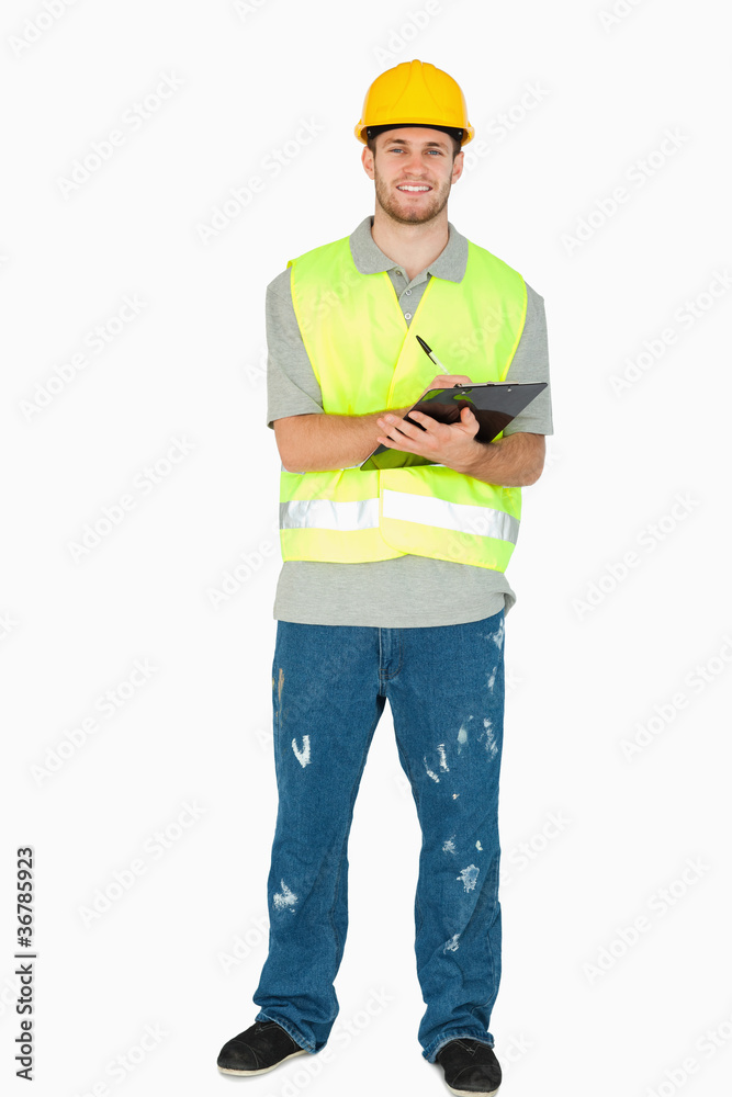 Smiling young construction worker taking notes Smiling young construction worker taking notes