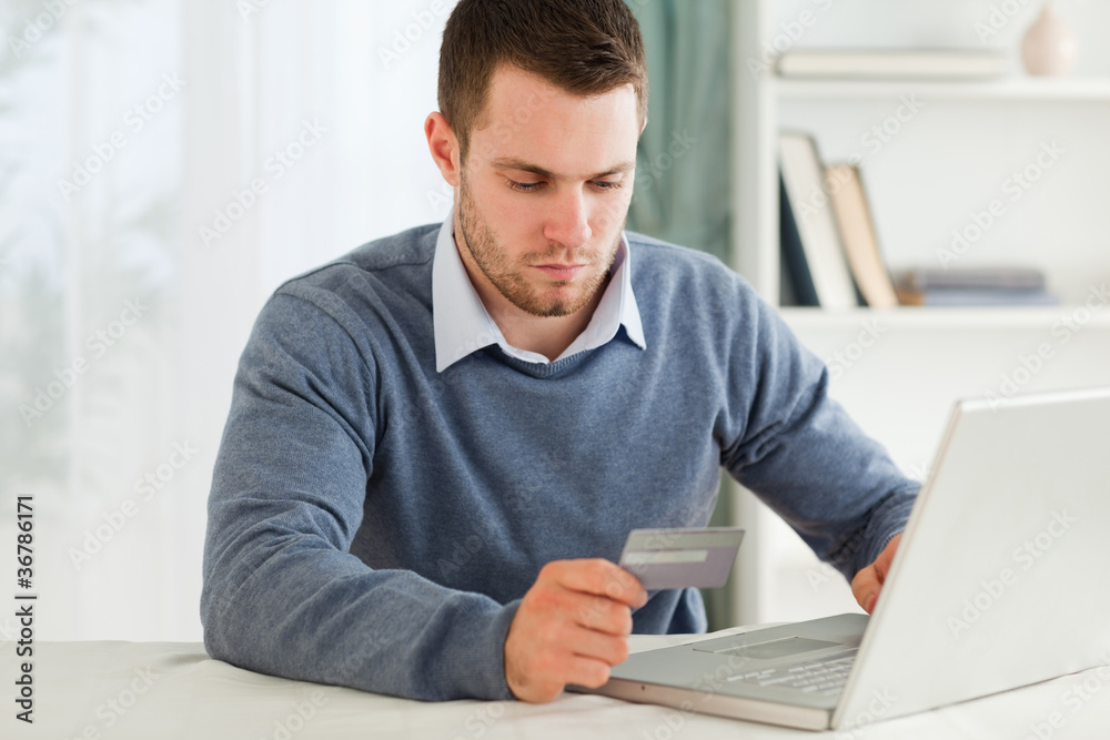 Male entering credit card information in his notebook Male entering credit card information in his notebook