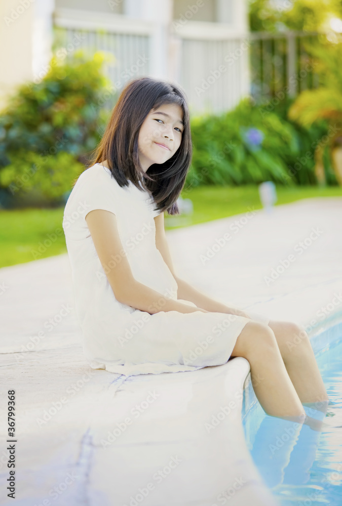 Ten year old girl repaxing by swimming pool, smiling Ten year old girl repaxing by swimming pool, smiling