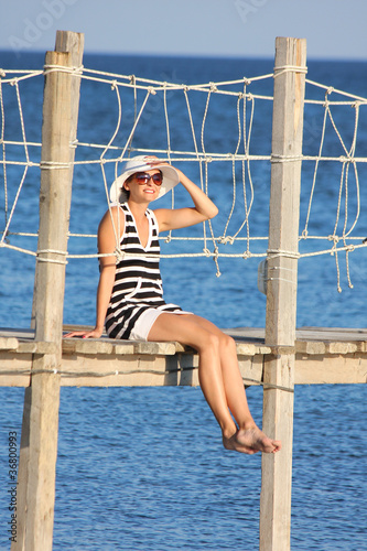 Woman during summer vacation on bridge above sea