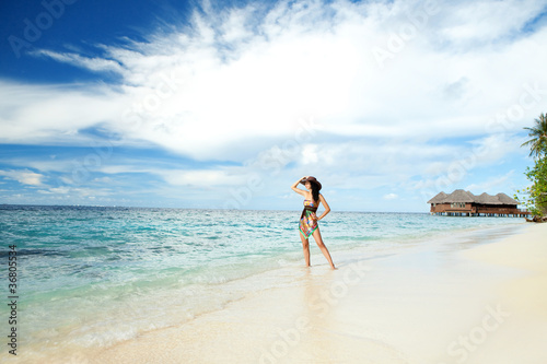 Tranquil woman on the tropical beach with bungalows