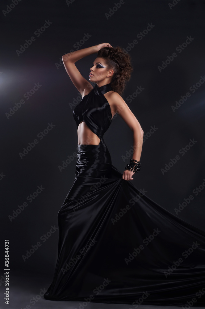 Woman in black long dress over dark background Woman in black long dress over dark background