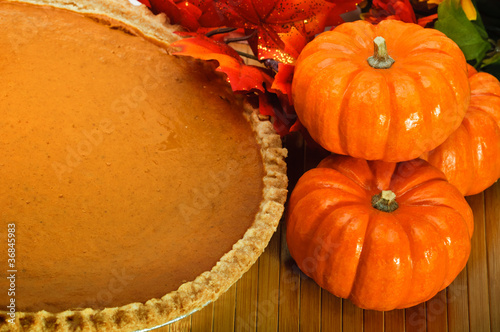 Pumpkin pie with autumn leaves and pumpkins.