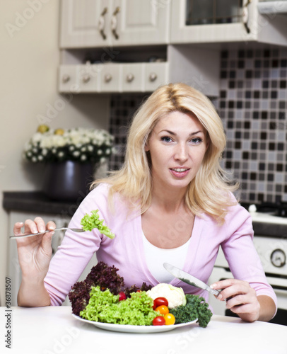 Pretty blonde woman eating some vegetables